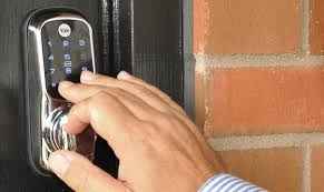 Main d’un serrurier Francheville manipulant une serrure connectée sur une porte, intervention sur système électronique et sécurisation d’accès à Francheville.